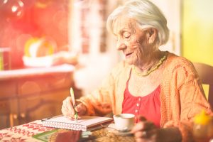 Rentnerin in ihrer Wohnung, schreibend am Tisch