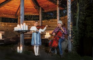 Zwei Kinder musizieren in weihnachtlicher Hütte