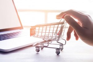 Mini-Einkaufswagen vor Laptops als Symbol für das Einkaufen online