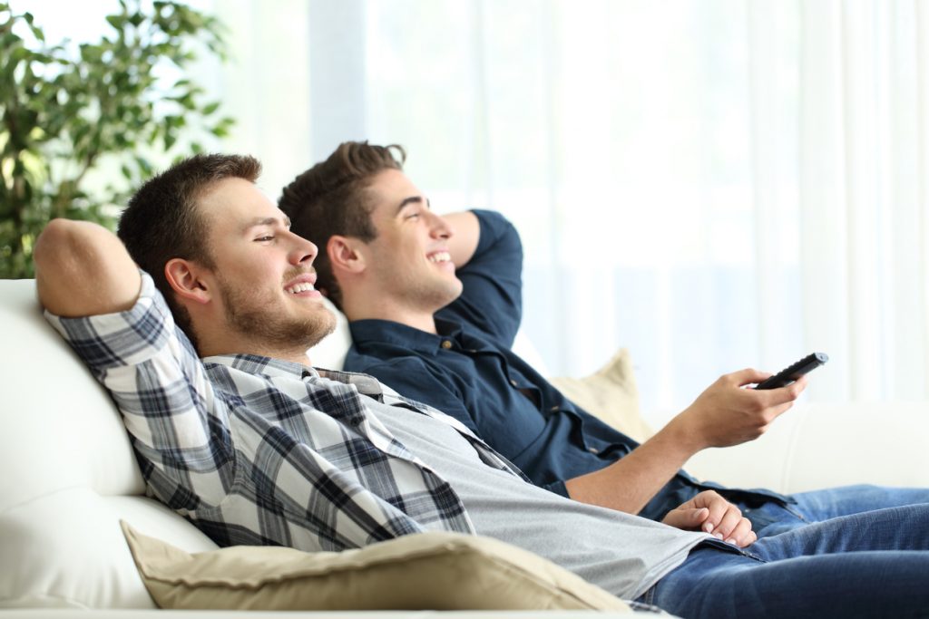 Junge Männer schauen mit reduzierten Rundfunkbeitrag TV